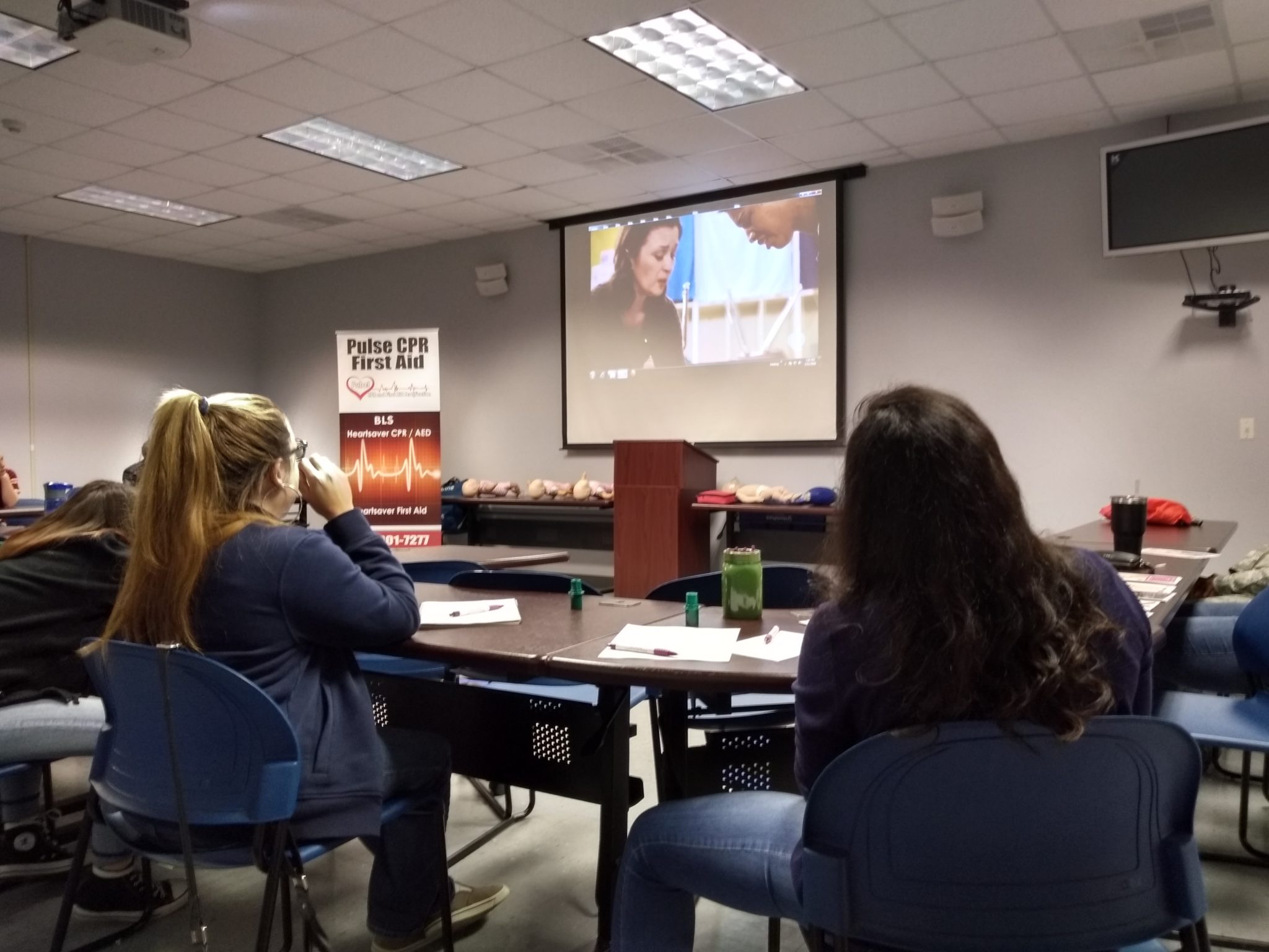 A classroom scene featuring a group of individuals seated at tables, engaged in discussion and learning activities_Workplace CPR training near me