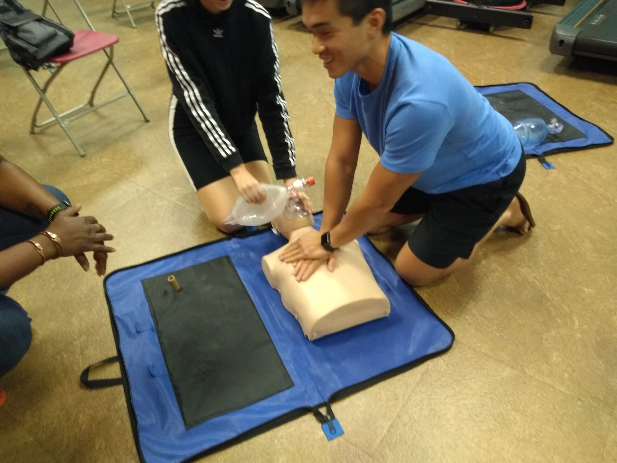 A woman helps a man position a CPR dummy in Augusta, GA, highlighting essential skills for heart attack emergencies_BLS near me