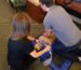 A man and woman perform emergency CPR on a man lying on the ground, demonstrating life-saving techniques_AHA CPR BLS Augusta