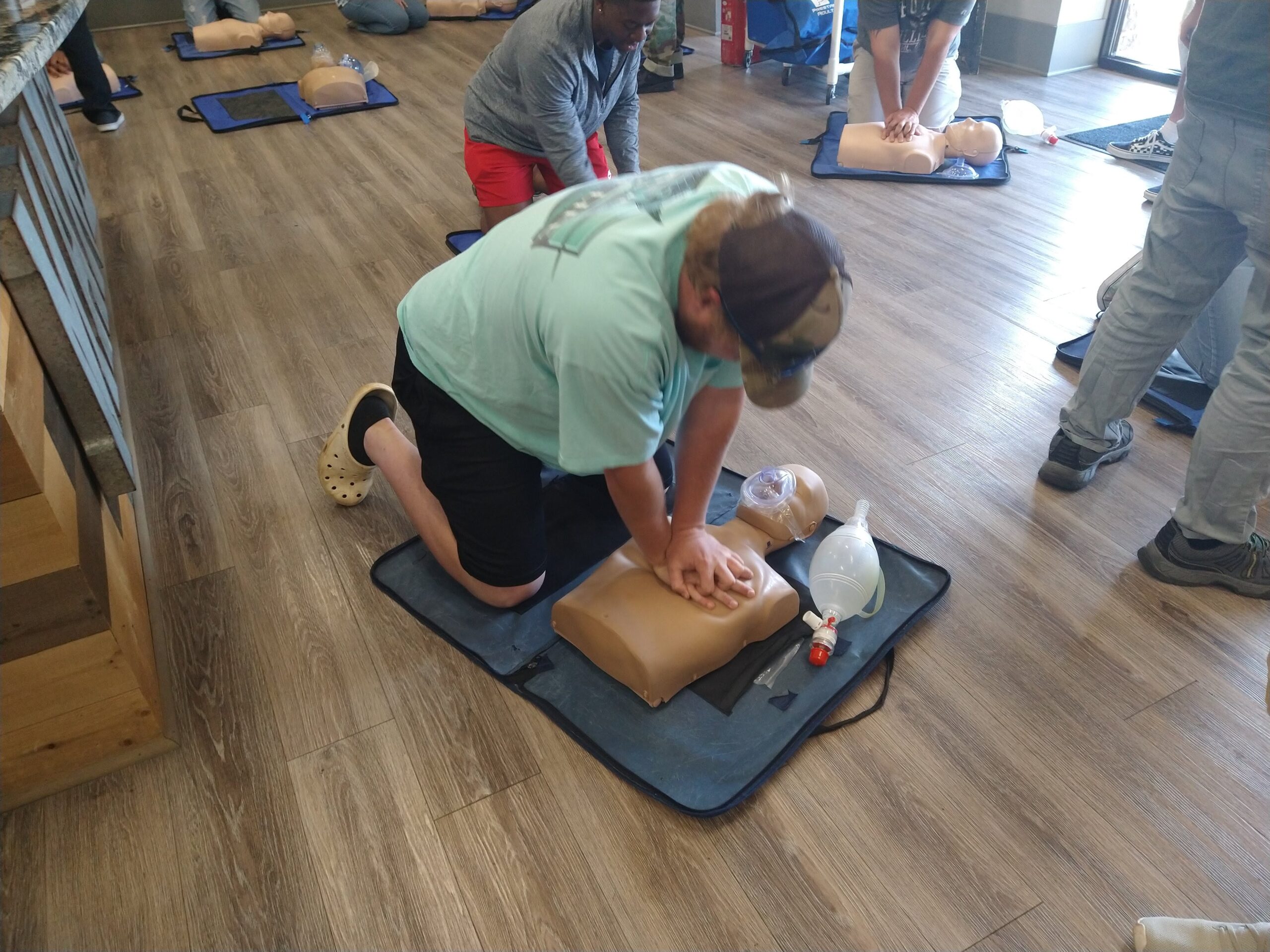 A woman performs an exercise on a mannequin, showcasing proper form and technique in a training environment.