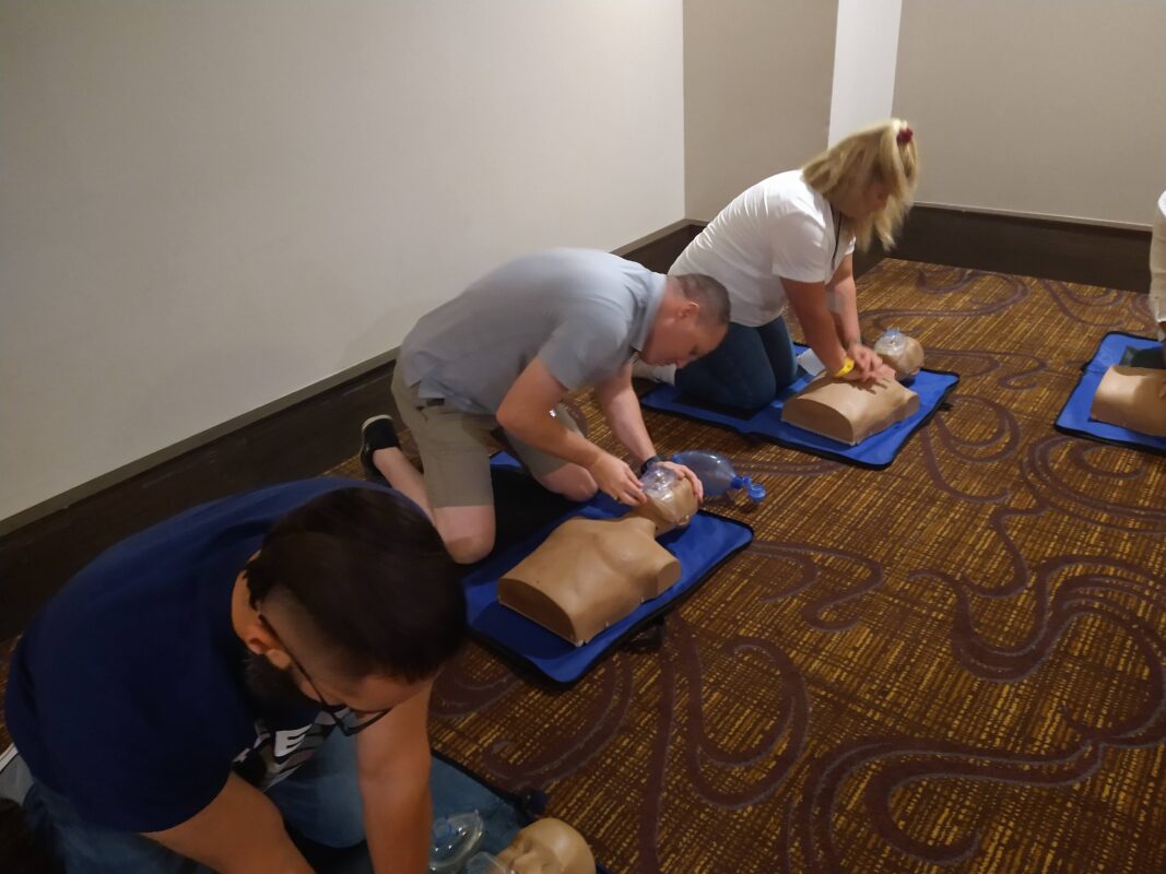 Several people engaged in CPR training using a simulation machine in a professional environment_AHA CPR classes online_Corporate CPR training